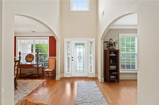entryway featuring wood finished floors, visible vents, crown molding, and baseboards