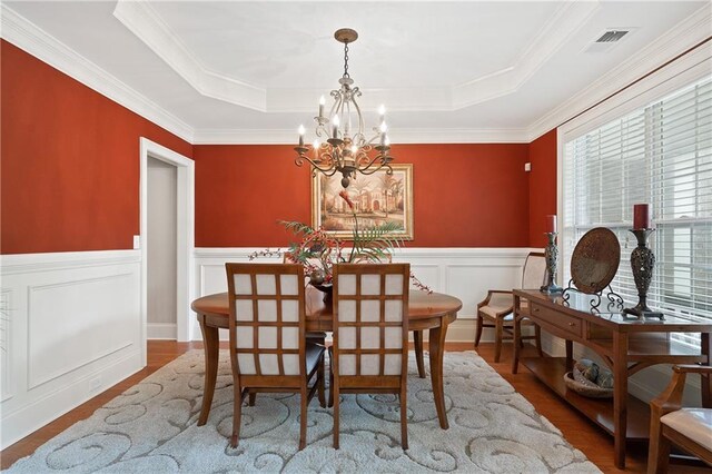 dining area with an inviting chandelier, wood finished floors, a raised ceiling, and visible vents