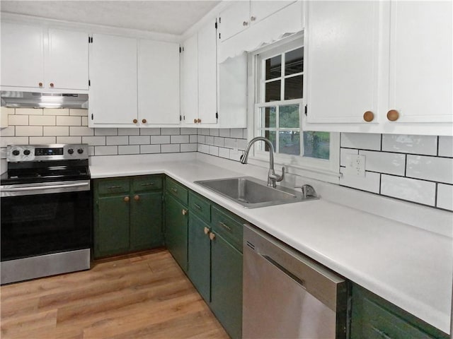 kitchen featuring sink, tasteful backsplash, white cabinetry, appliances with stainless steel finishes, and light hardwood / wood-style floors