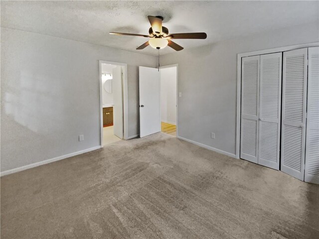 unfurnished bedroom with a closet, a textured ceiling, ceiling fan, ensuite bathroom, and light carpet