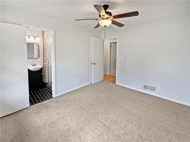 unfurnished bedroom featuring light carpet, ensuite bath, ceiling fan, and sink