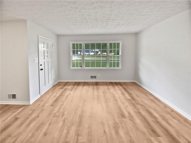 unfurnished room featuring a textured ceiling and light hardwood / wood-style flooring