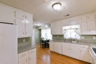 566 Sugar Valley Ln, Conyers, GA 30094 - kitchen with stove, a sink, white cabinets, light wood finished floors, and white fridge