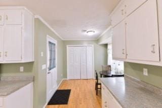 566 Sugar Valley Ln, Conyers, GA 30094 - kitchen with ornamental molding, light countertops, white cabinetry, and light wood finished floors