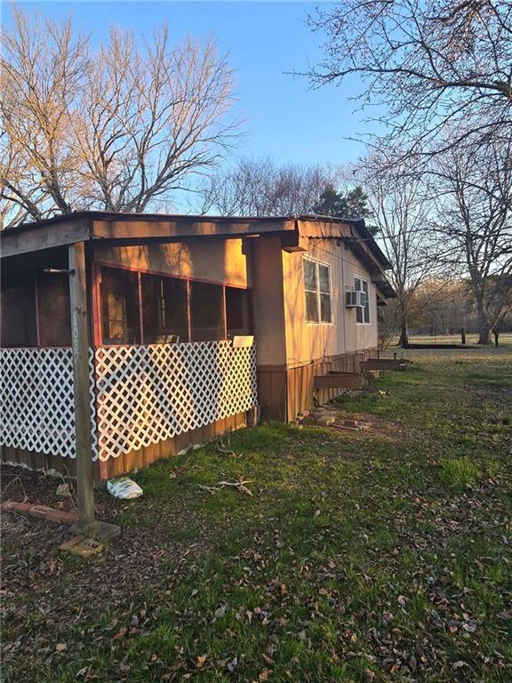 view of home's exterior with a sunroom and a yard