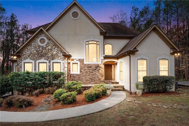 french country home featuring brick siding and stucco siding