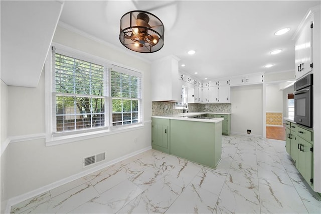 kitchen with green cabinetry, a peninsula, visible vents, and oven