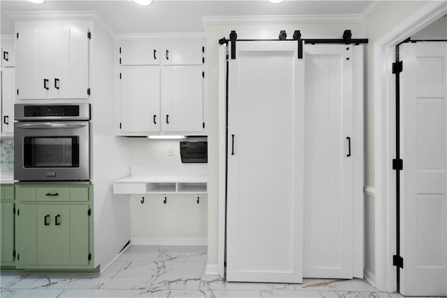 kitchen with green cabinetry, oven, a barn door, white cabinetry, and ornamental molding