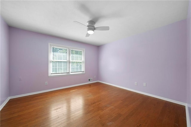 unfurnished room with baseboards, a ceiling fan, visible vents, and hardwood / wood-style flooring