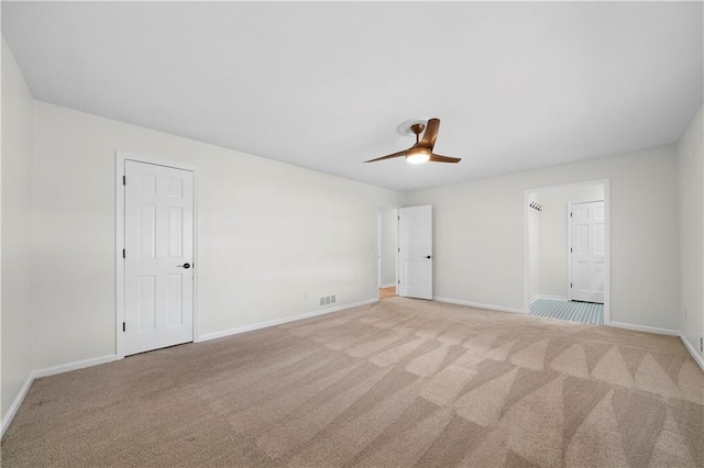 spare room featuring visible vents, baseboards, ceiling fan, and light carpet