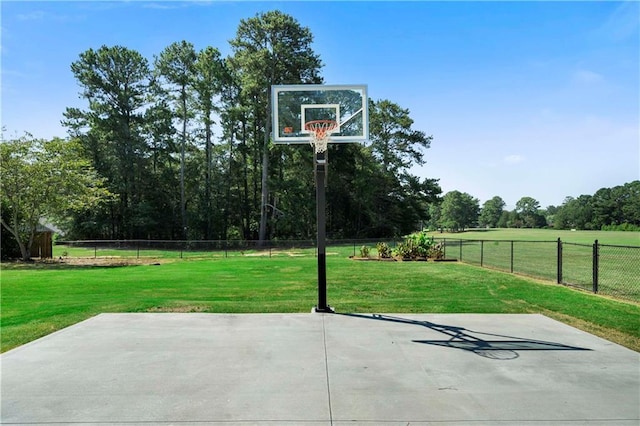 view of sport court with a yard, basketball hoop, and fence