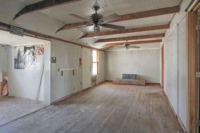 unfurnished living room featuring beam ceiling, wood finished floors, and ceiling fan