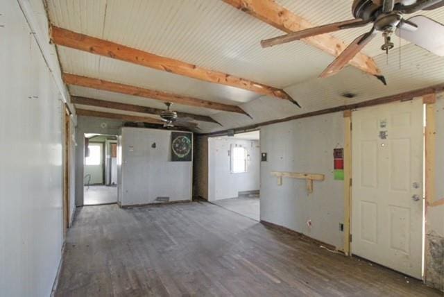 unfurnished room featuring beam ceiling, plenty of natural light, ceiling fan, and wood finished floors