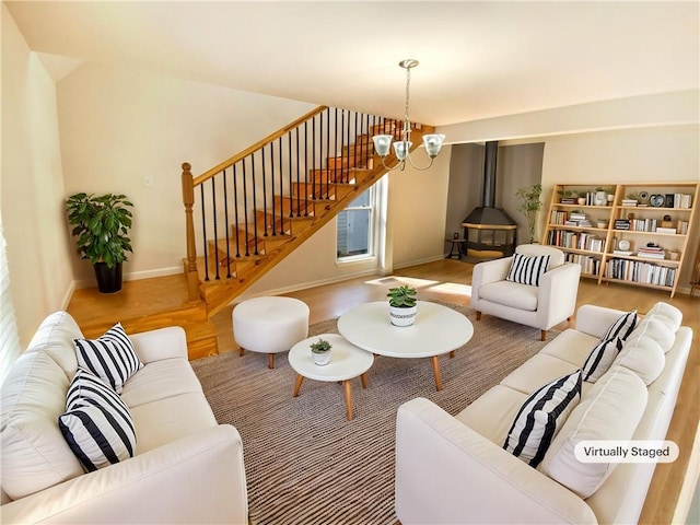 living area featuring stairs, baseboards, wood finished floors, and a notable chandelier