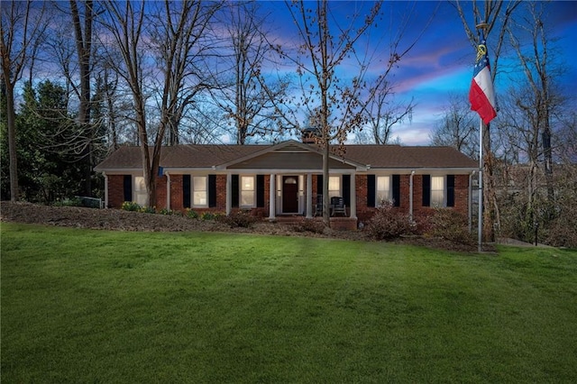 single story home featuring a front yard, brick siding, and a chimney