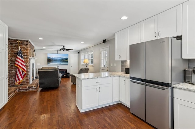 kitchen with white cabinets, open floor plan, dark wood-type flooring, freestanding refrigerator, and a peninsula