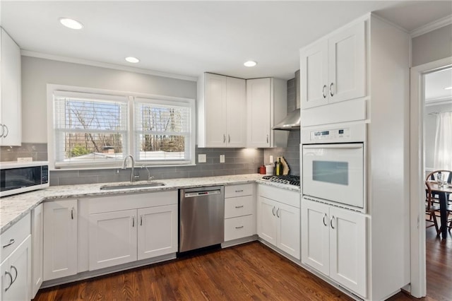 kitchen featuring a sink, white cabinetry, ornamental molding, appliances with stainless steel finishes, and dark wood finished floors