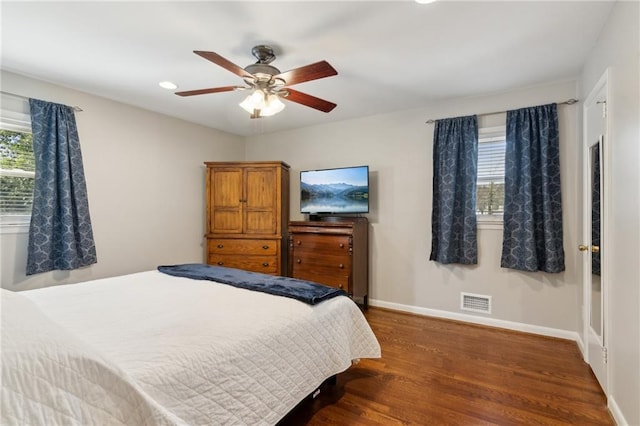 bedroom with multiple windows, wood finished floors, visible vents, and baseboards