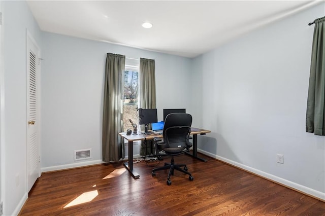 office space with baseboards, visible vents, and wood finished floors