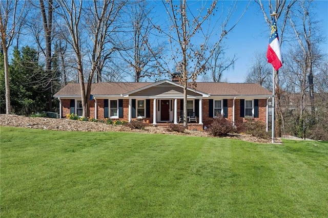 ranch-style home with brick siding, a chimney, and a front yard