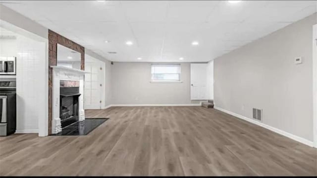 unfurnished living room featuring visible vents, baseboards, wood finished floors, and a fireplace