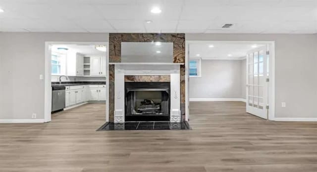 living area with visible vents, baseboards, light wood-style flooring, and a fireplace