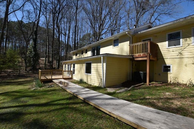 view of side of home with a yard, brick siding, and a deck