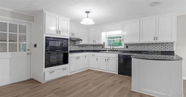 kitchen with a sink, black appliances, white cabinets, under cabinet range hood, and dark countertops