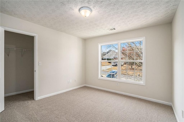 unfurnished bedroom featuring a textured ceiling, carpet floors, and a closet