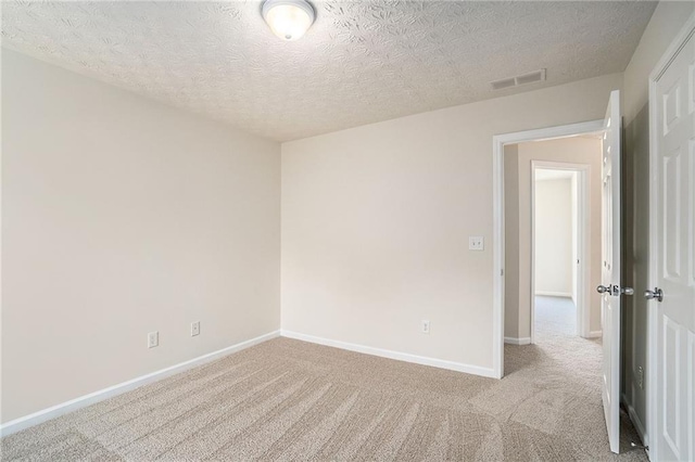 spare room featuring a textured ceiling and light colored carpet