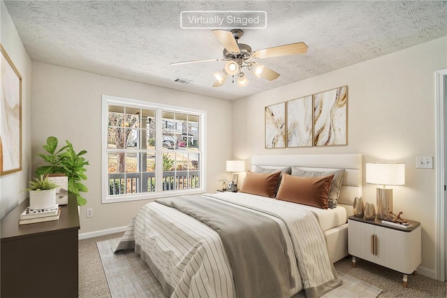 bedroom with a textured ceiling, carpet floors, and ceiling fan