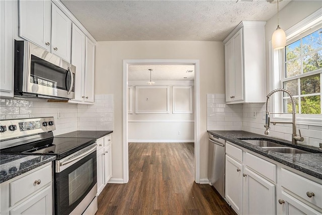 kitchen featuring hanging light fixtures, sink, a textured ceiling, appliances with stainless steel finishes, and white cabinetry