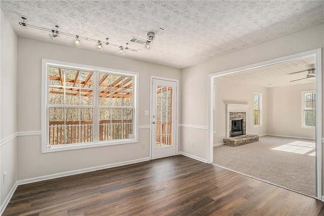 unfurnished living room featuring dark hardwood / wood-style flooring, track lighting, and ceiling fan