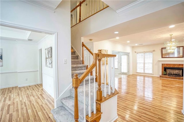 stairway featuring a fireplace, hardwood / wood-style floors, a chandelier, and ornamental molding