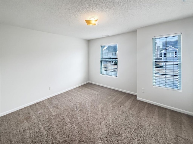 spare room featuring carpet floors, baseboards, and a textured ceiling