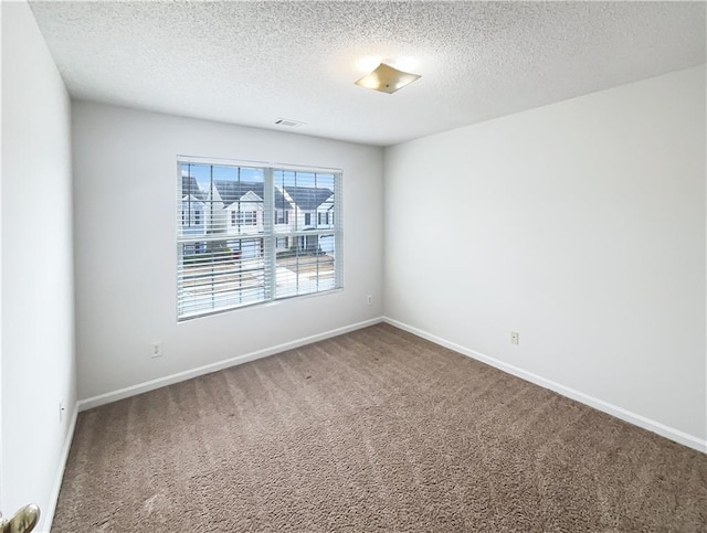 carpeted spare room with visible vents, a textured ceiling, and baseboards
