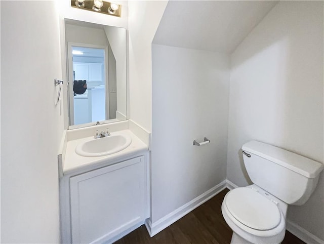 bathroom featuring toilet, baseboards, wood finished floors, and vanity