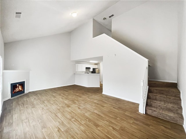 unfurnished living room with hardwood / wood-style flooring and high vaulted ceiling