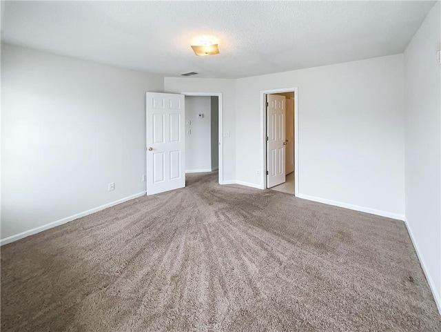 empty room with carpet, visible vents, a textured ceiling, and baseboards