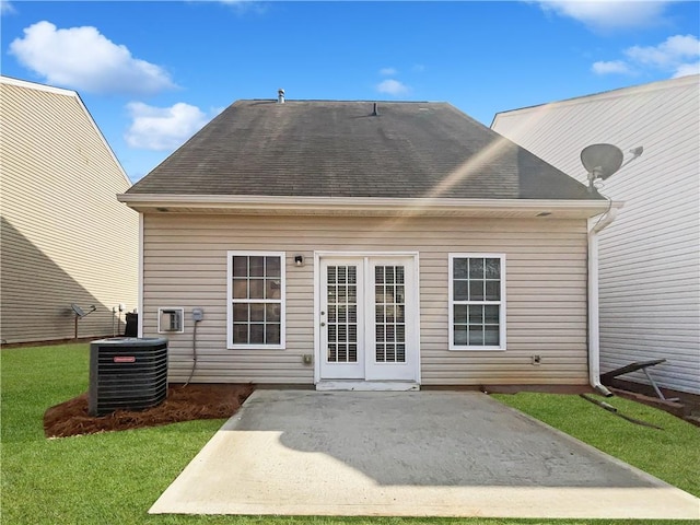 back of house featuring roof with shingles, central AC unit, a lawn, and a patio area