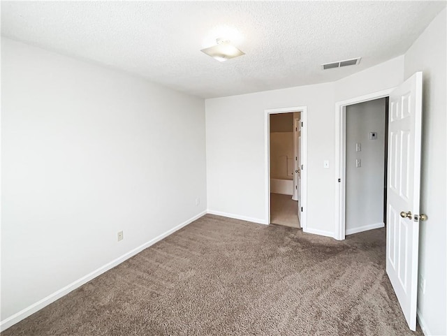 unfurnished bedroom featuring dark colored carpet, visible vents, a textured ceiling, and baseboards