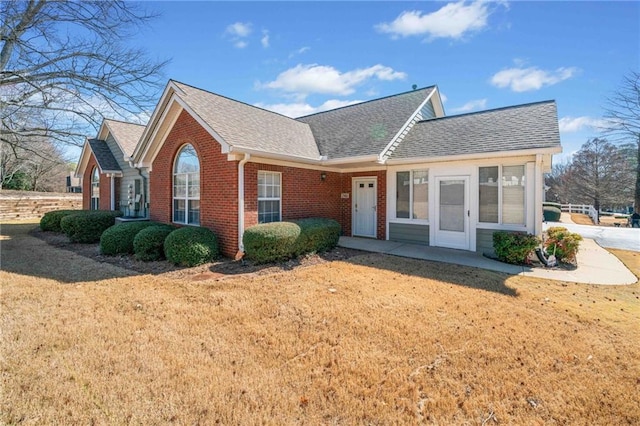 view of front facade featuring a front yard, brick siding, and a shingled roof