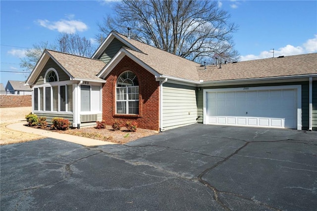 ranch-style house with brick siding, roof with shingles, a garage, a sunroom, and driveway