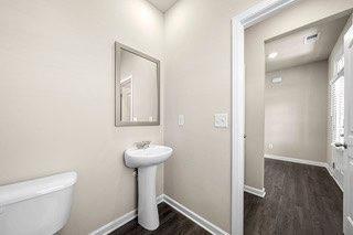 bathroom featuring baseboards, wood finished floors, and toilet