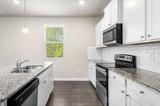 kitchen featuring decorative backsplash, baseboards, dark wood-type flooring, a sink, and appliances with stainless steel finishes