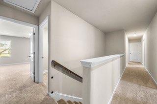 corridor featuring carpet floors, baseboards, and an upstairs landing