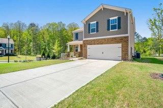 view of front of home with concrete driveway, brick siding, a front yard, and a garage