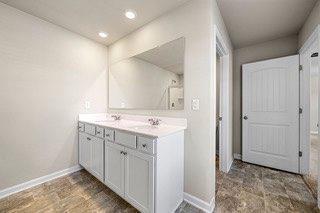 full bath featuring double vanity, baseboards, recessed lighting, and a sink
