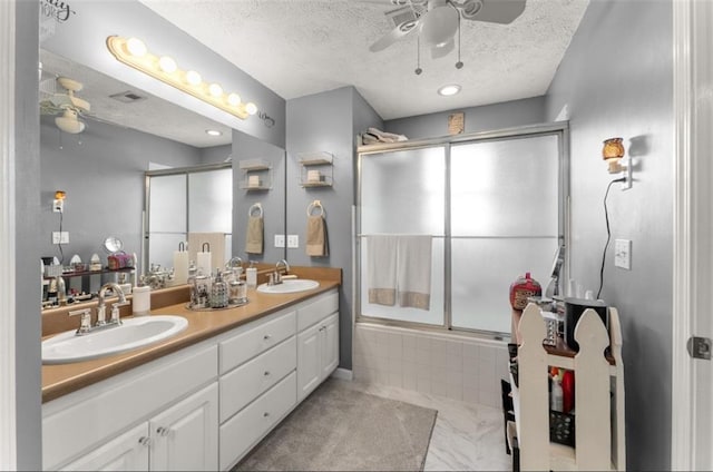 bathroom with vanity, a textured ceiling, ceiling fan, and enclosed tub / shower combo