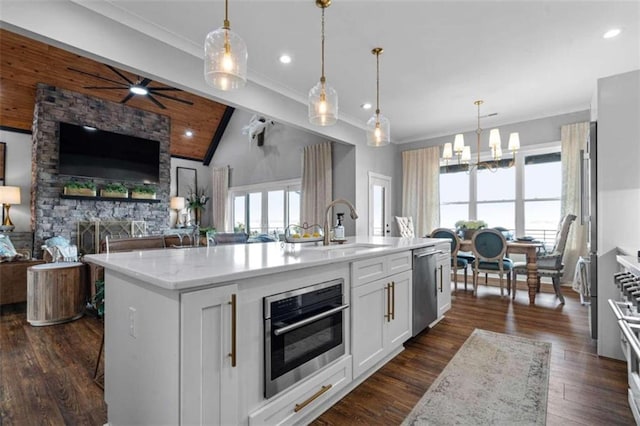 kitchen with white cabinetry, appliances with stainless steel finishes, decorative light fixtures, and a kitchen island with sink